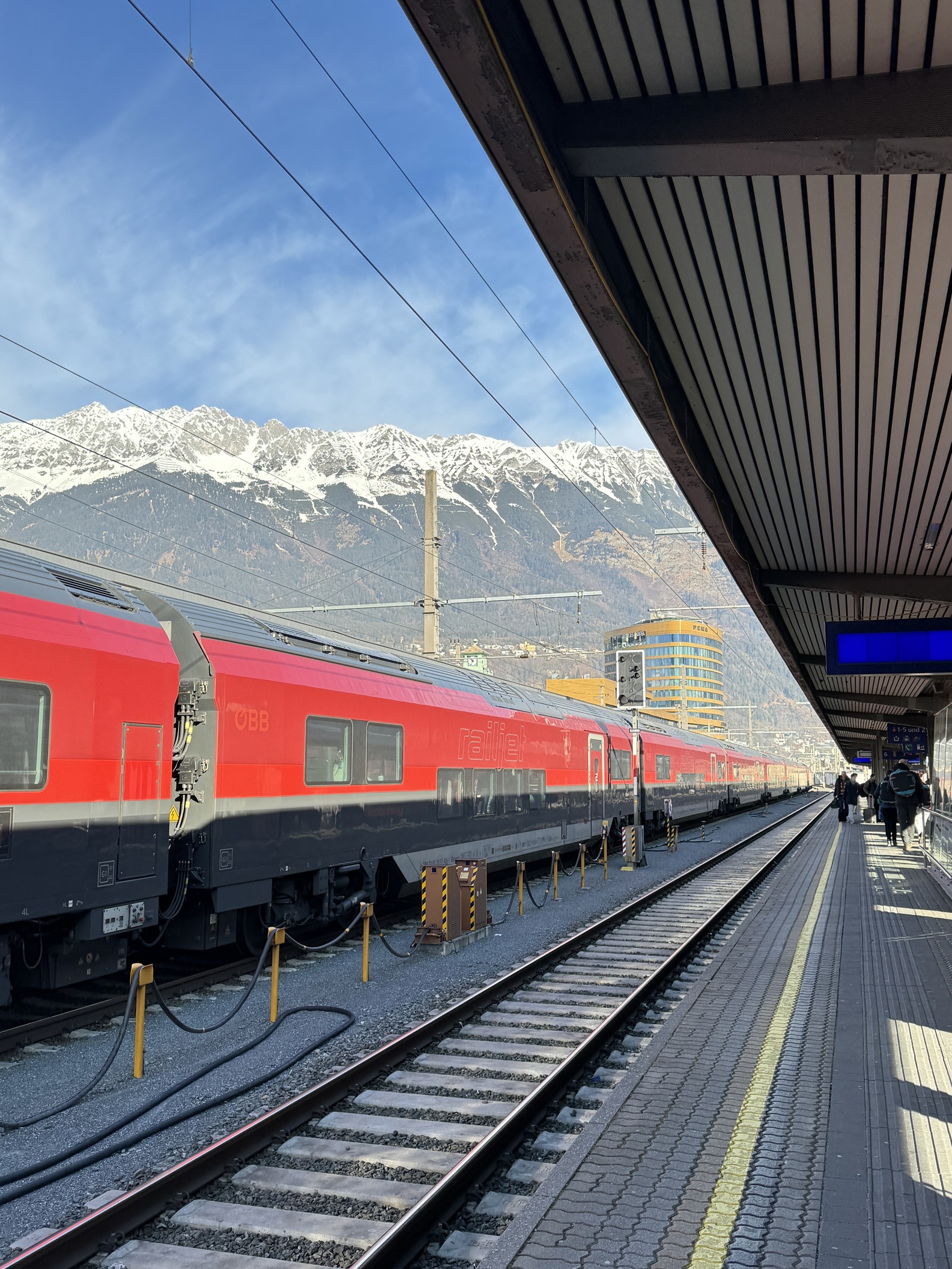 A train platform at Innsbruck Hauptbanhof, with snowy mountains in the distance