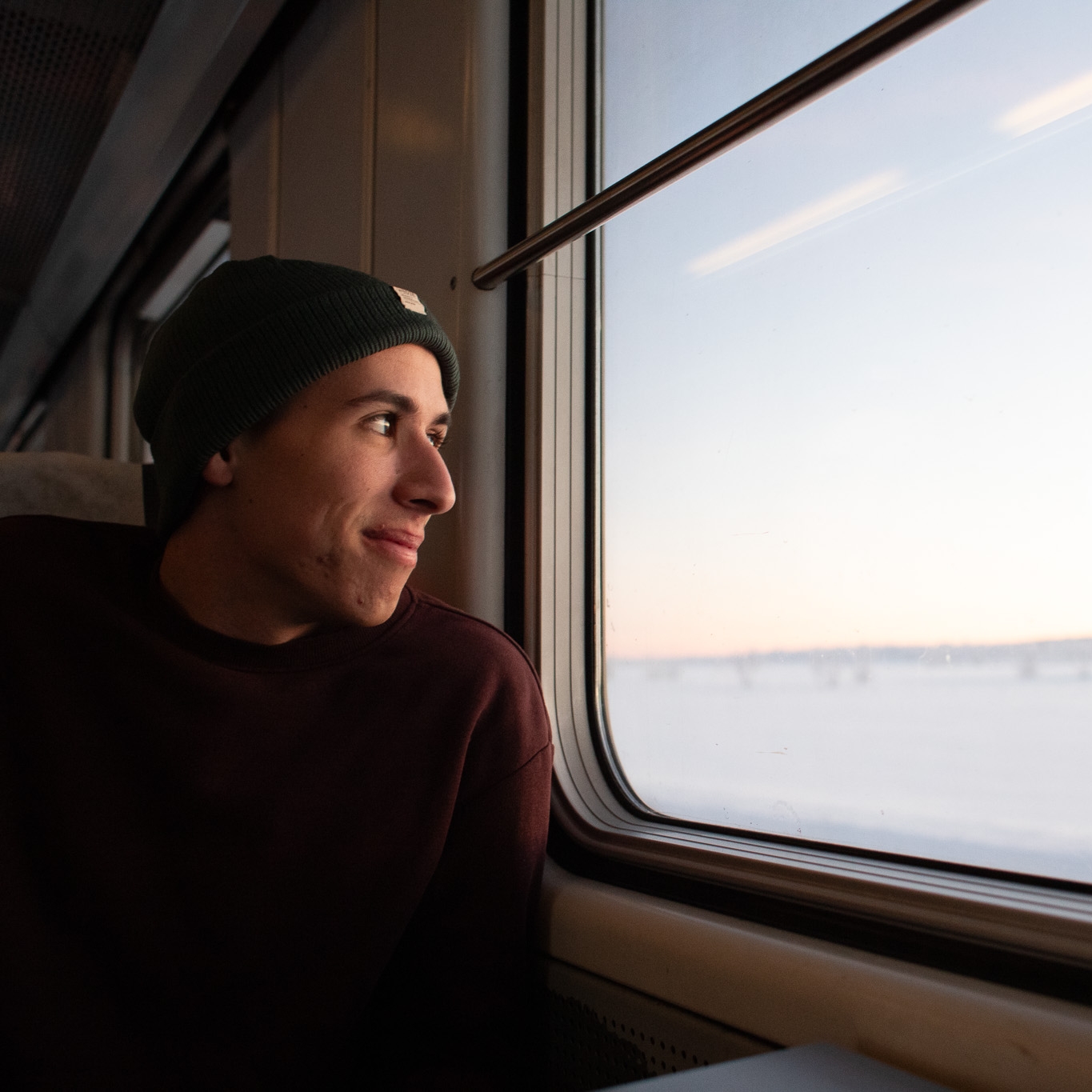 Cristian looks out the window of a train at a snowy field