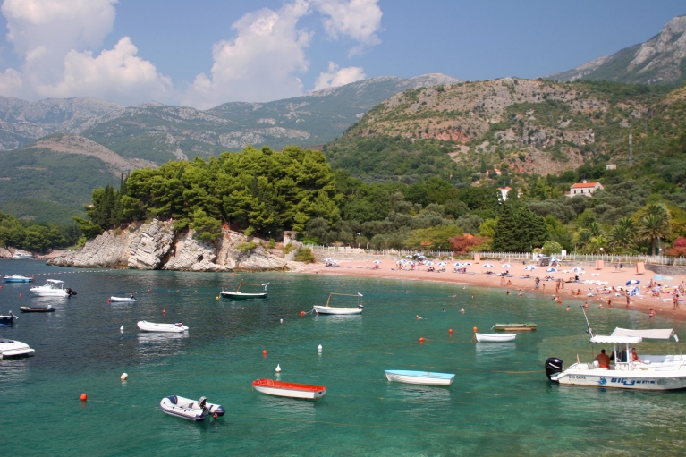 Barcos quietos en aguas color cerceta a lo largo de una exuberante costa en Bar, Montenegro