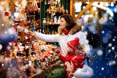 Los MEJORES 5 destinos europeos en invierno | Una madre con sus hijos comprando en un mercado navideño en Alemania