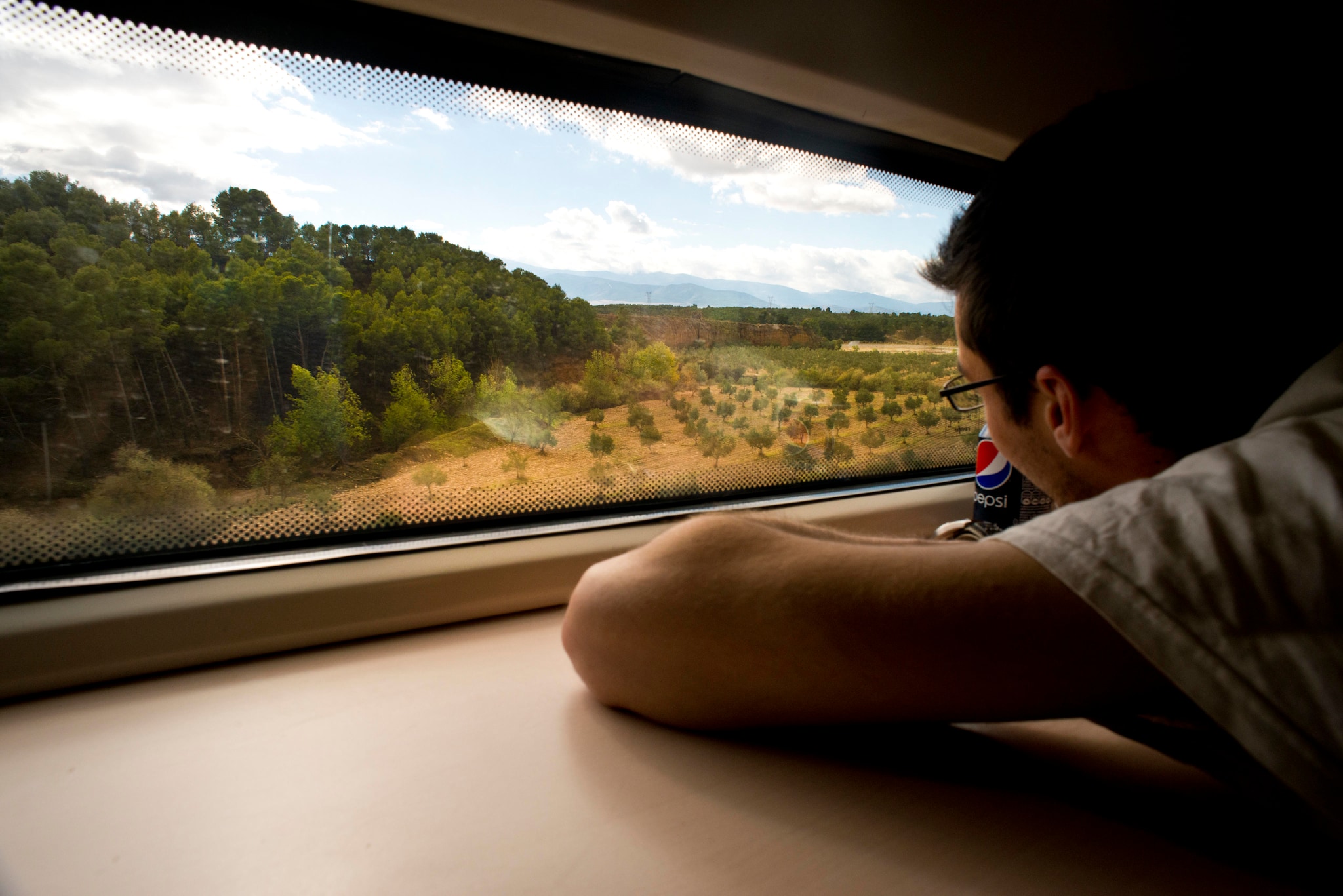 Hombre mirando un paisaje panorámico desde la ventana del tren AVE, Almería-Granada, España