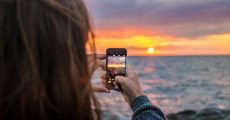 why_eurail_is_your_greenest_choice_-_female_taking_a_photo_of_sunset_with_mobile_at_vang_hasle_in_denmark