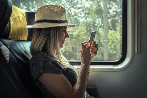 woman_sitting_at_train_and_looking_to_mobil_phone_under_sunlight_at_day_time