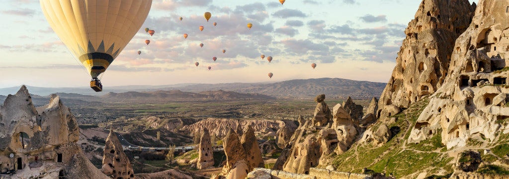 1_week_in_turkey_-_wide_panoramic_view_of_cappadocia_landscape_with_hot_air_balloons_flying_over_mountain_peaks_in_turkey_desktop