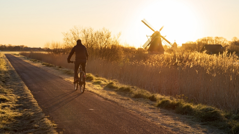netherlands-cyclist-bike-lane-sunset-windmill
