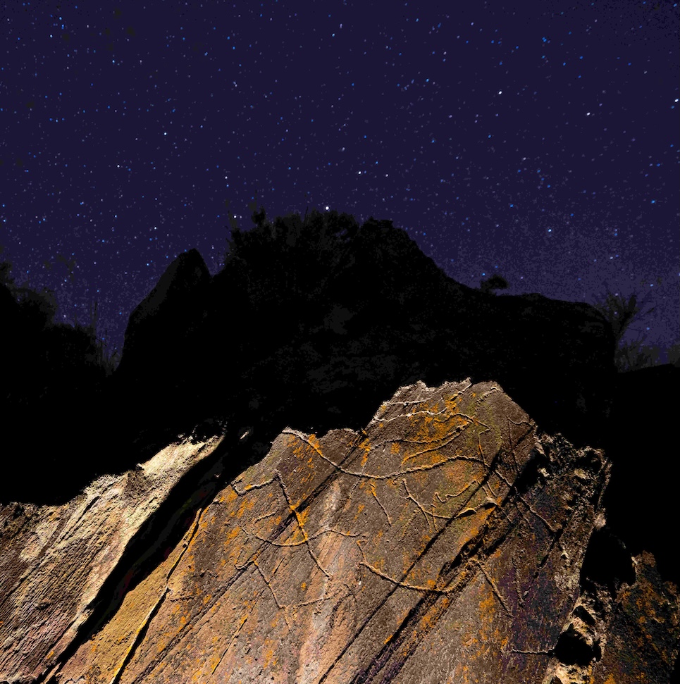 Prehistoric rock art illuminated by a flashlight at night