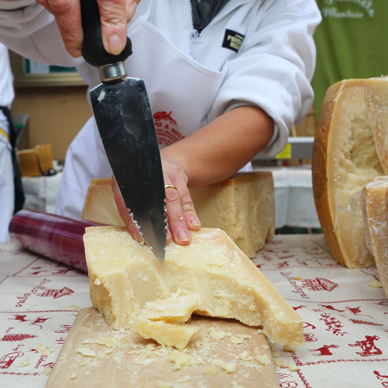 Un primer plano de un chef cortando un trozo de queso parmesano