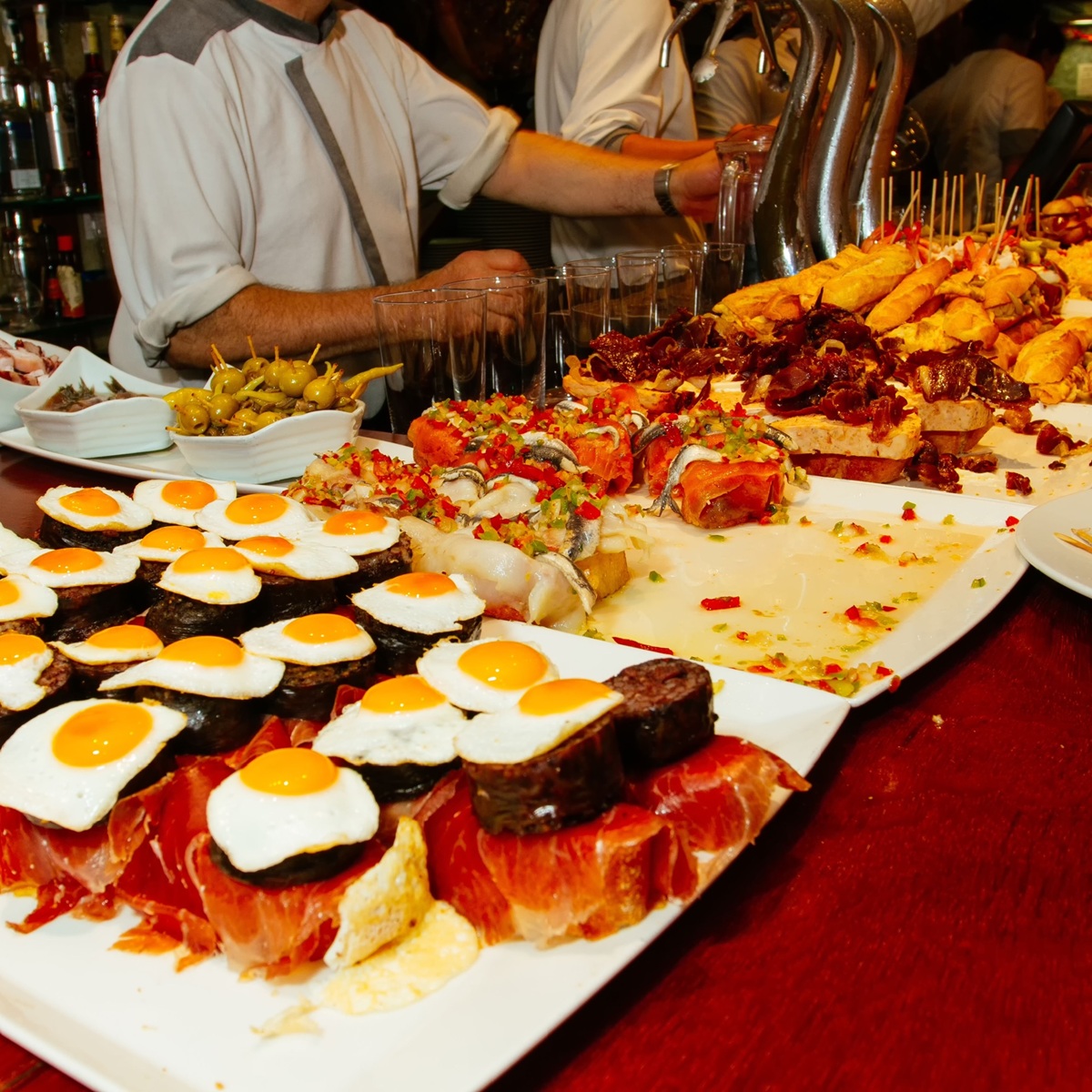 Un primer plano de pequeños platos de huevo, carne, queso y verduras sujetos con palillos sobre una mesa larga