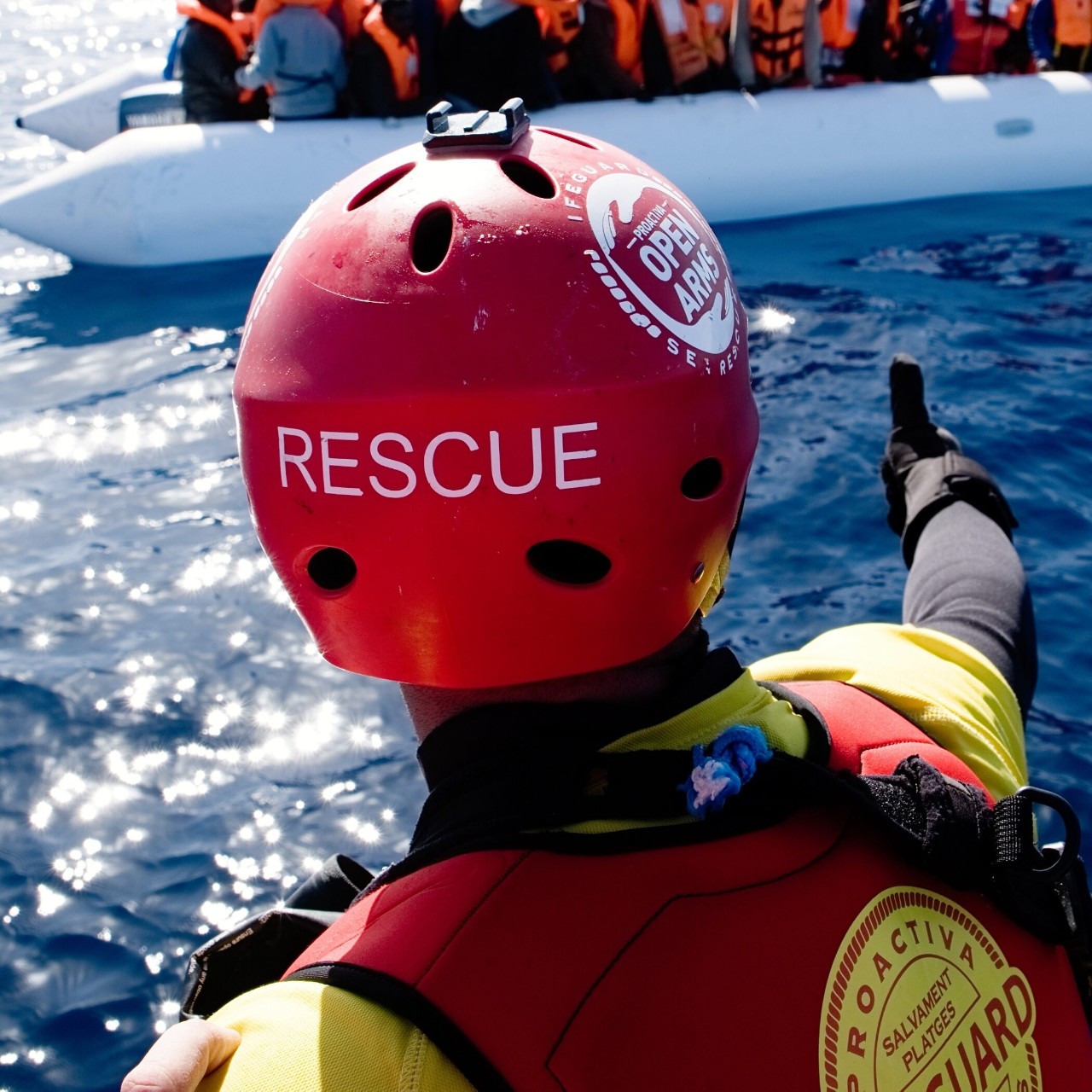 &quot;Rescue&quot; 라고 적힌 헬멧을 쓰고 보트를 향해 엄지손가락을 치켜세우고 있는 사람