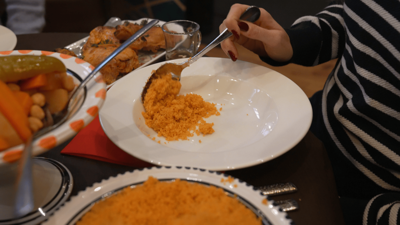 A person spoons couscous onto a plate