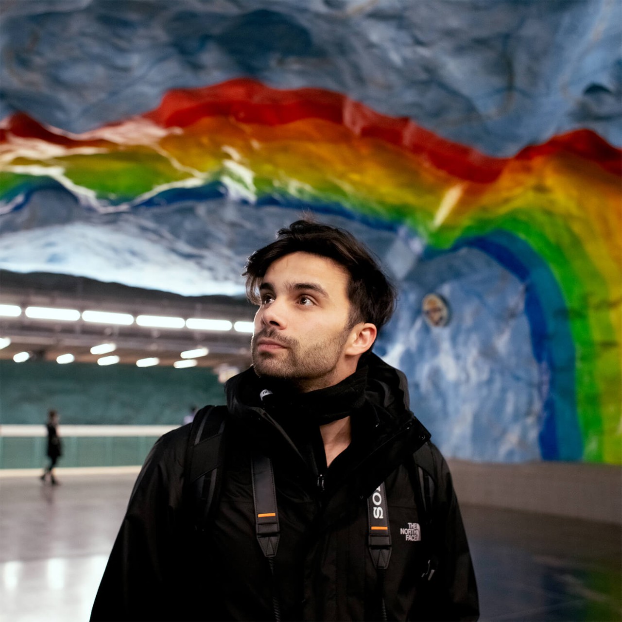 Uma pessoa admirando a arte colorida em uma estação de metrô em Estocolmo
